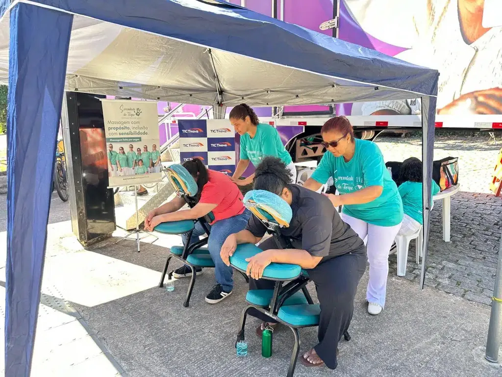 Pessoas recebendo massagem gratuita em uma ação da TIC Trens em parceria com a clínica Serenidade do Toque