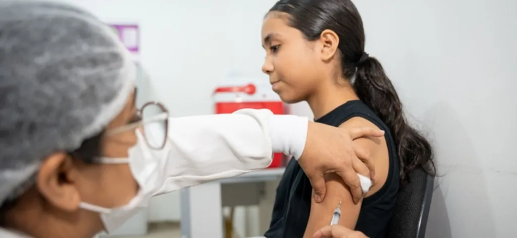Menina sendo vacinada por uma enfermeira